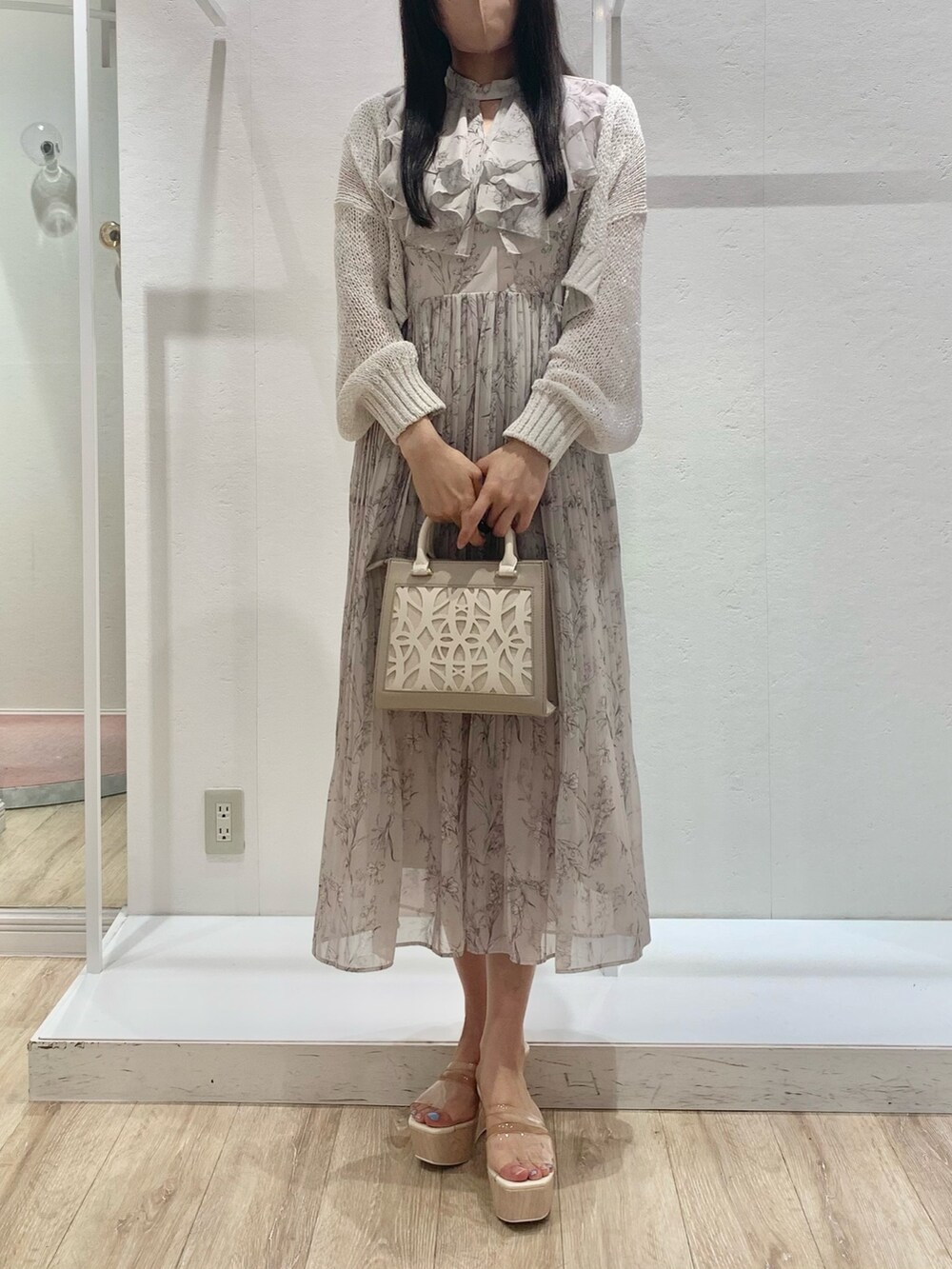 ベージュ系のショルダーバッグ、ピンク系のワンピース、ホワイト系のカーディガン/ボレロを着用したレディースの春コーディネートの2枚目の写真