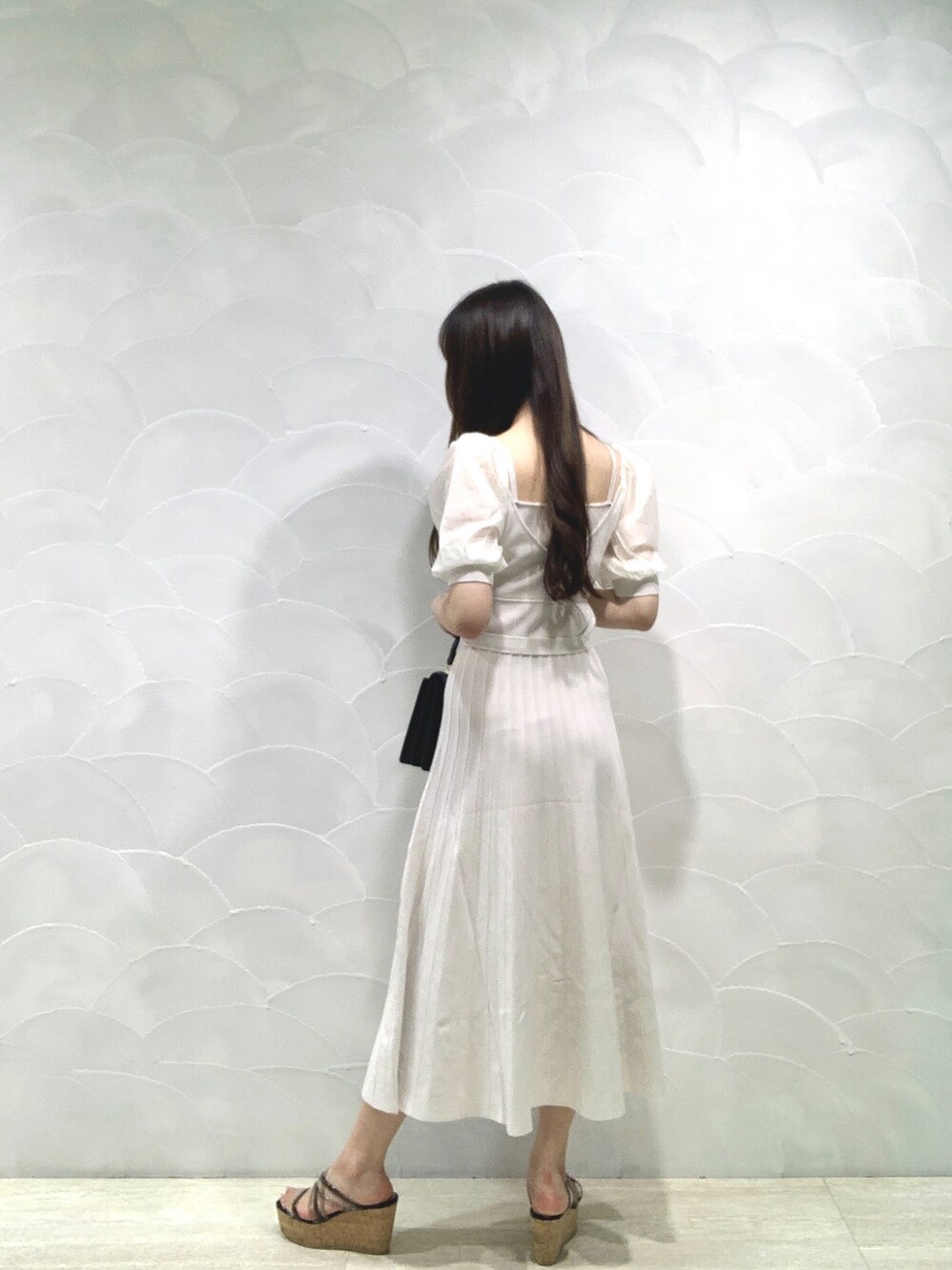 ブラック系のハンドバッグ、ホワイト系のワンピースを着用したレディースの夏コーディネートの3枚目の写真