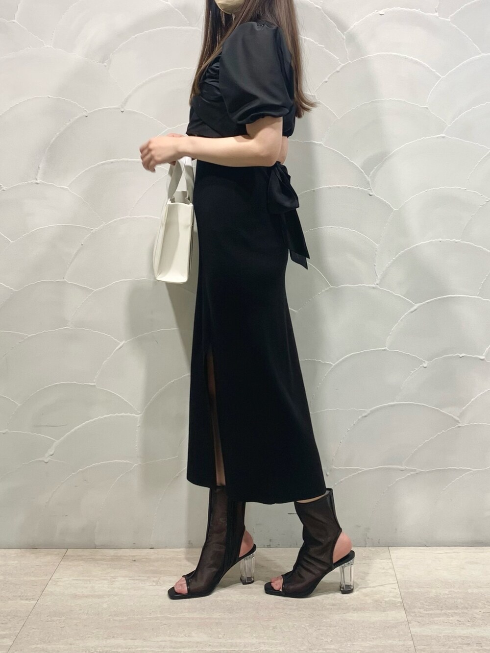 ホワイト系のトートバッグ、ブラック系のブーツ、ブラック系のワンピースを着用したレディースの春コーディネートの2枚目の写真