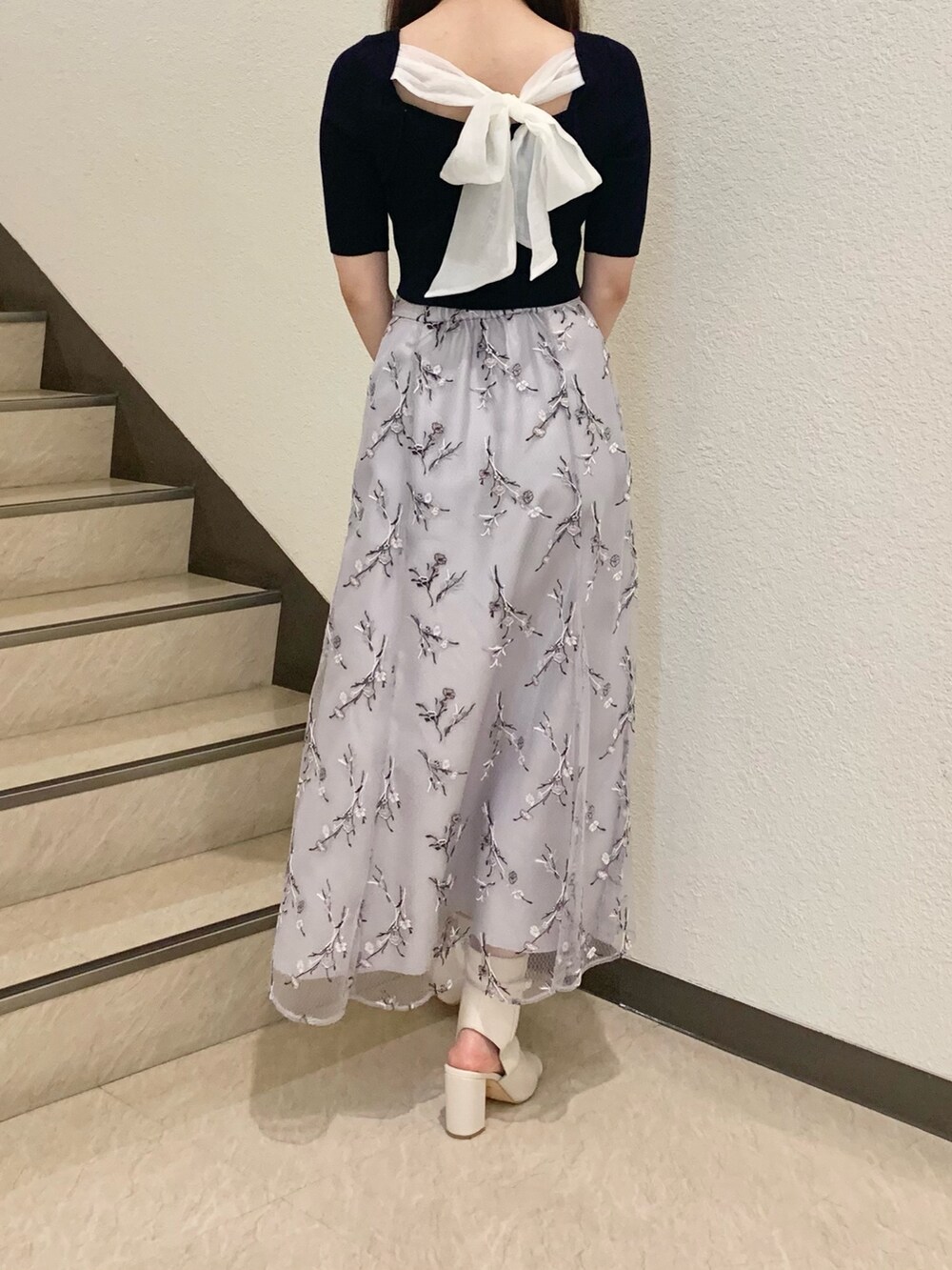 ホワイト系のハンドバッグ、ホワイト系のブーツ、パープル系のスカートを着用したレディースの春コーディネートの3枚目の写真