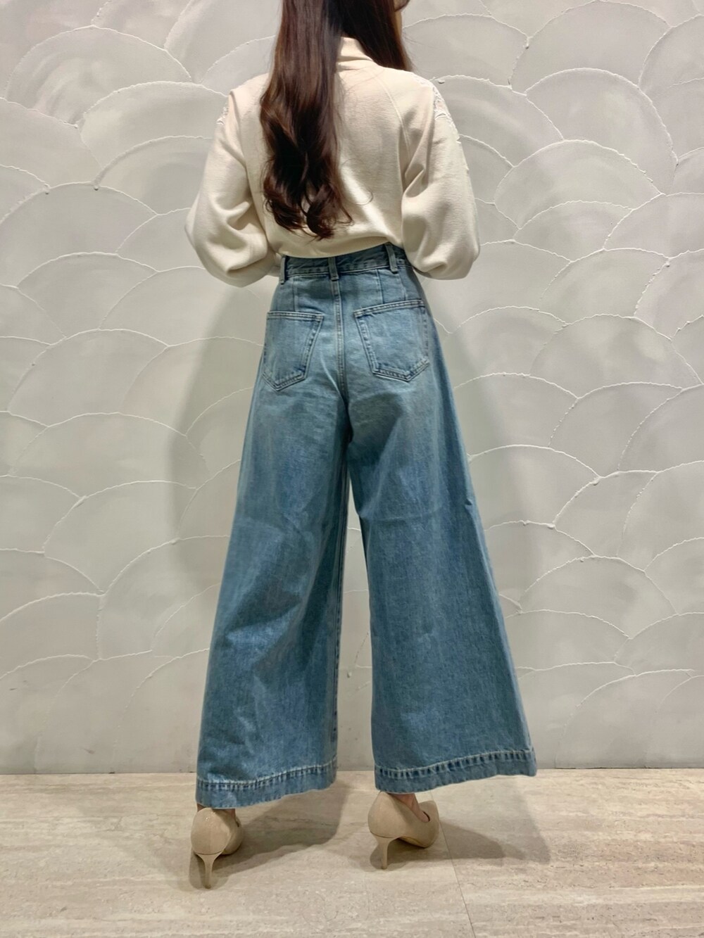 ホワイト系のニット/セーター、ホワイト系のパンプス、ブルー系のデニムパンツを着用したレディースの秋コーディネートの3枚目の写真