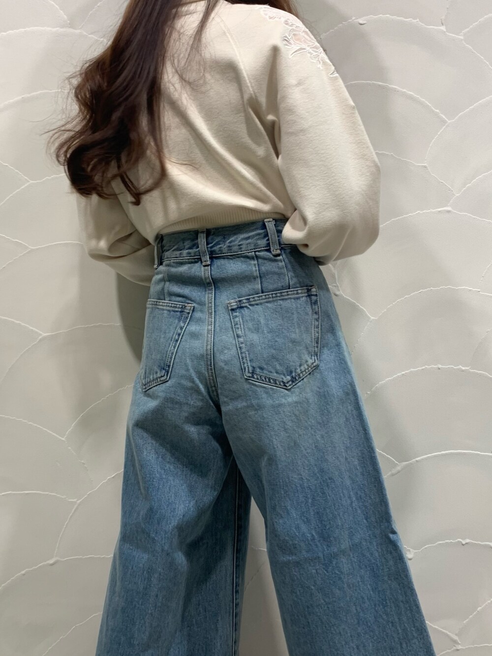 ホワイト系のニット/セーター、ホワイト系のパンプス、ブルー系のデニムパンツを着用したレディースの秋コーディネートの5枚目の写真