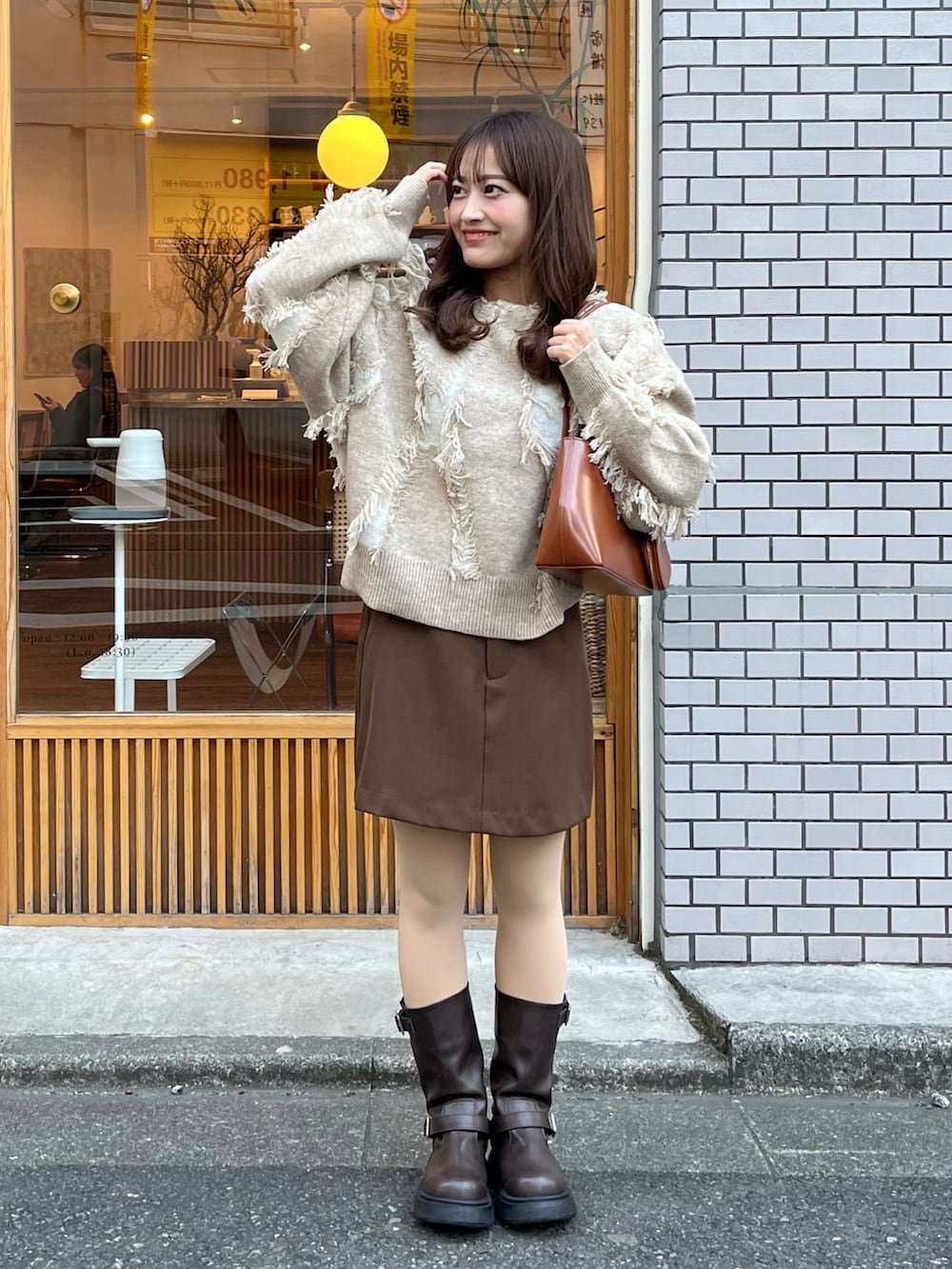 ブラウン系のスカート、ベージュ系のニット/セーター、ブラウン系のハンドバッグを着用したレディースの春コーディネートの3枚目の写真