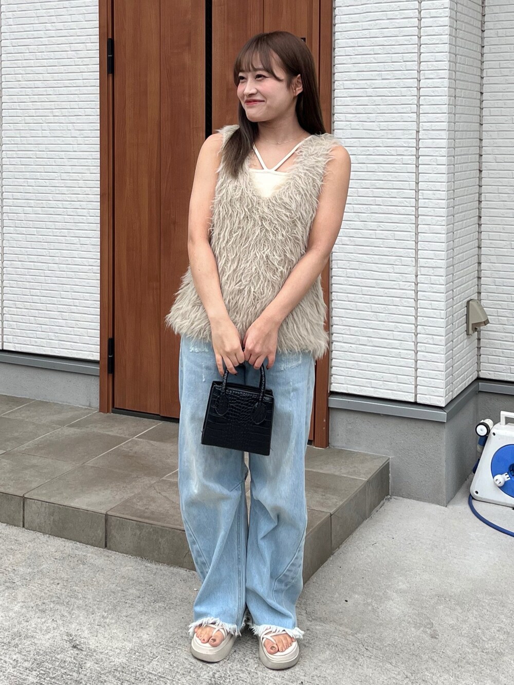 ベージュ系のベスト、ホワイト系のキャミソール、ブラック系のバッグを着用したレディースの夏コーディネートの3枚目の写真