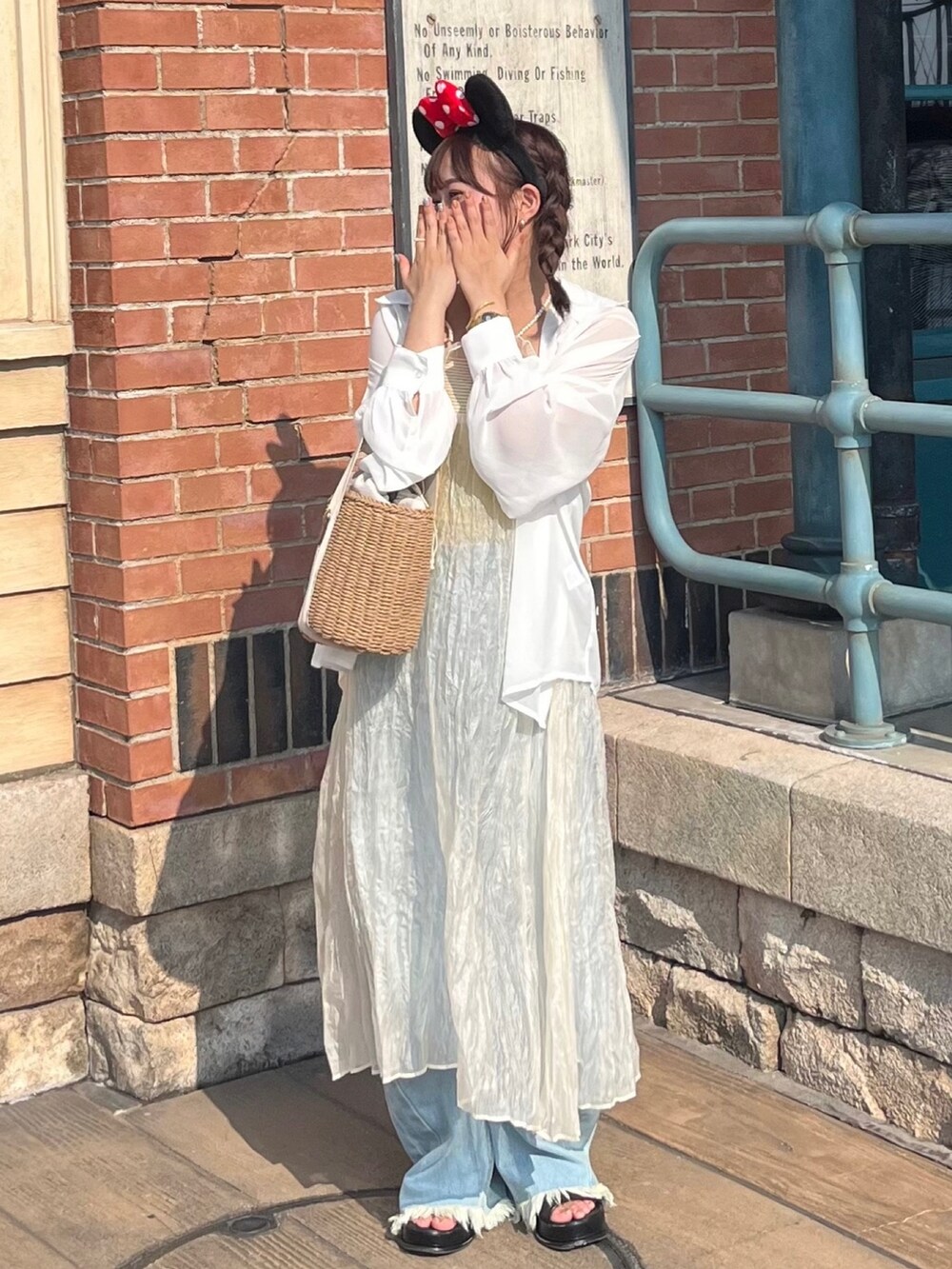 ホワイト系のワンピース、ブルー系のデニムパンツ、ブラック系のサンダルを着用したレディースの夏コーディネートの3枚目の写真