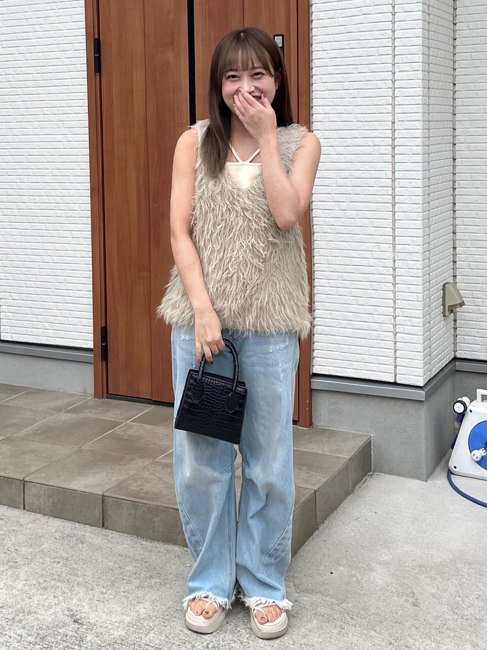 ベージュ系のベスト、ホワイト系のキャミソール、ブラック系のバッグを着用したレディースの夏コーディネートの2枚目の写真