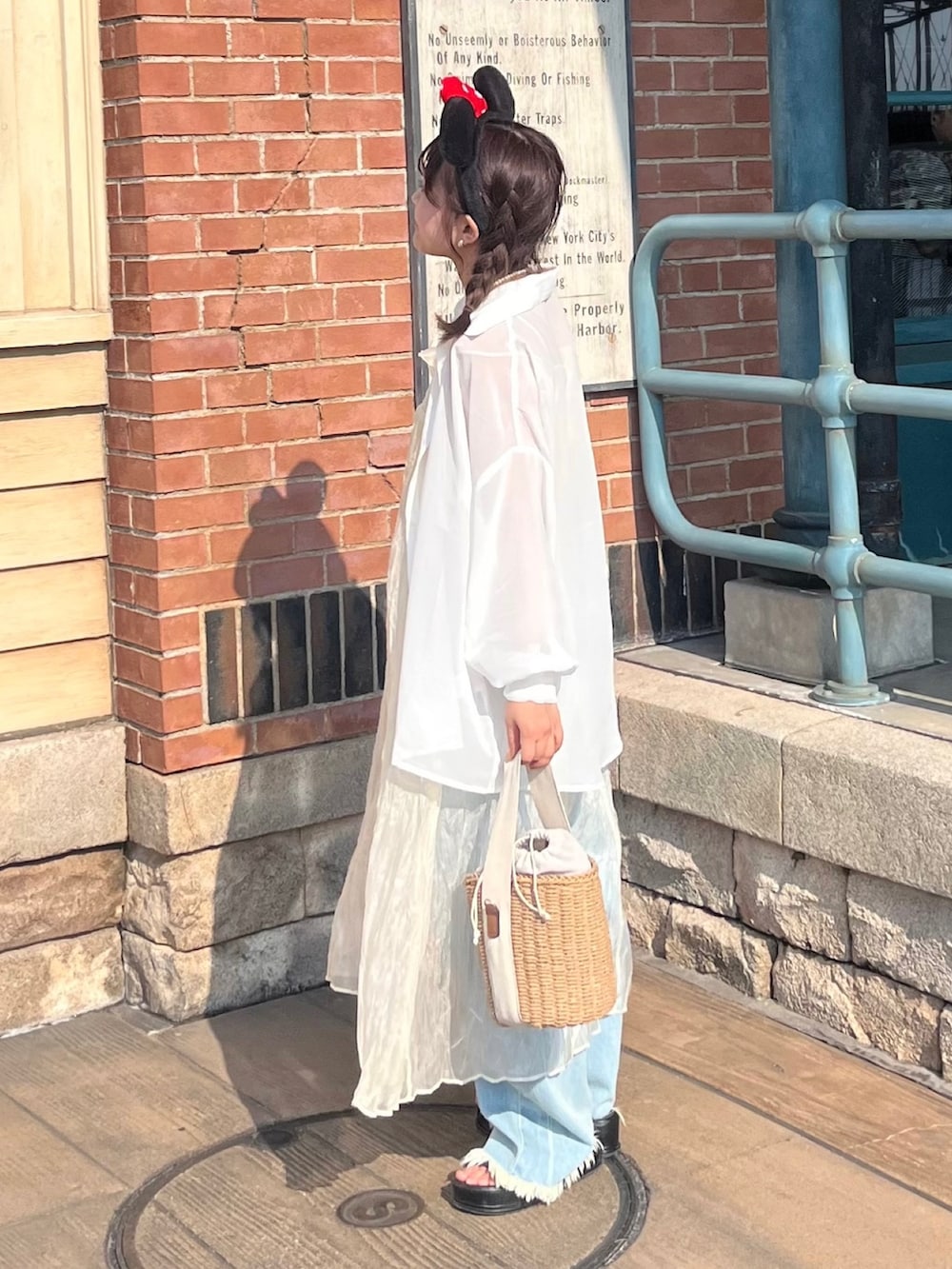 ホワイト系のワンピース、ブルー系のデニムパンツ、ブラック系のサンダルを着用したレディースの夏コーディネートの2枚目の写真