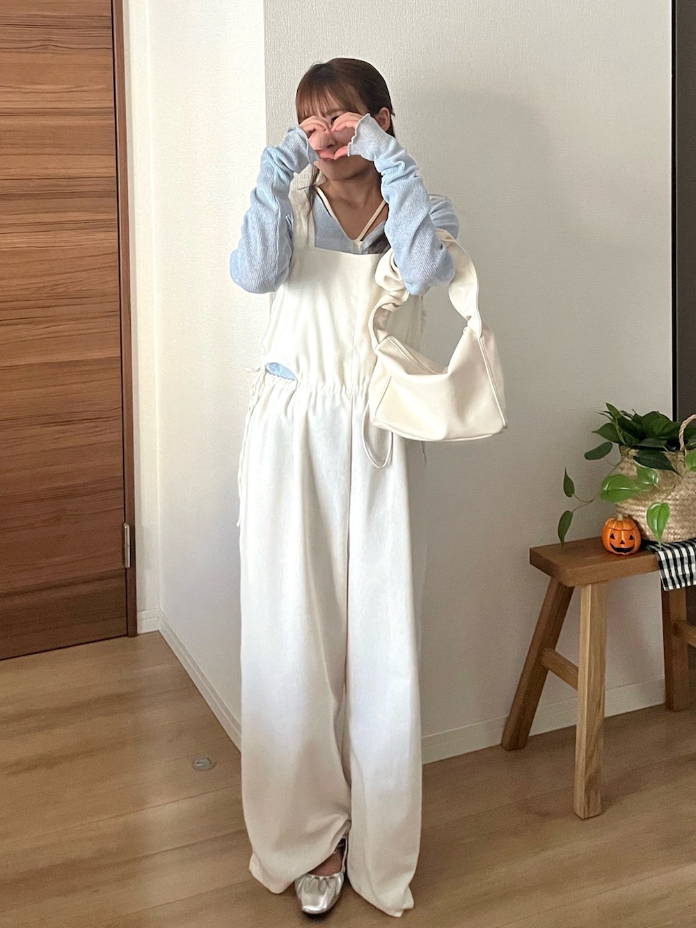 ホワイト系のハンドバッグ、ブルー系のTシャツ/カットソー、ホワイト系のサロペット/オーバーオールを着用したレディースの秋コーディネートの2枚目の写真