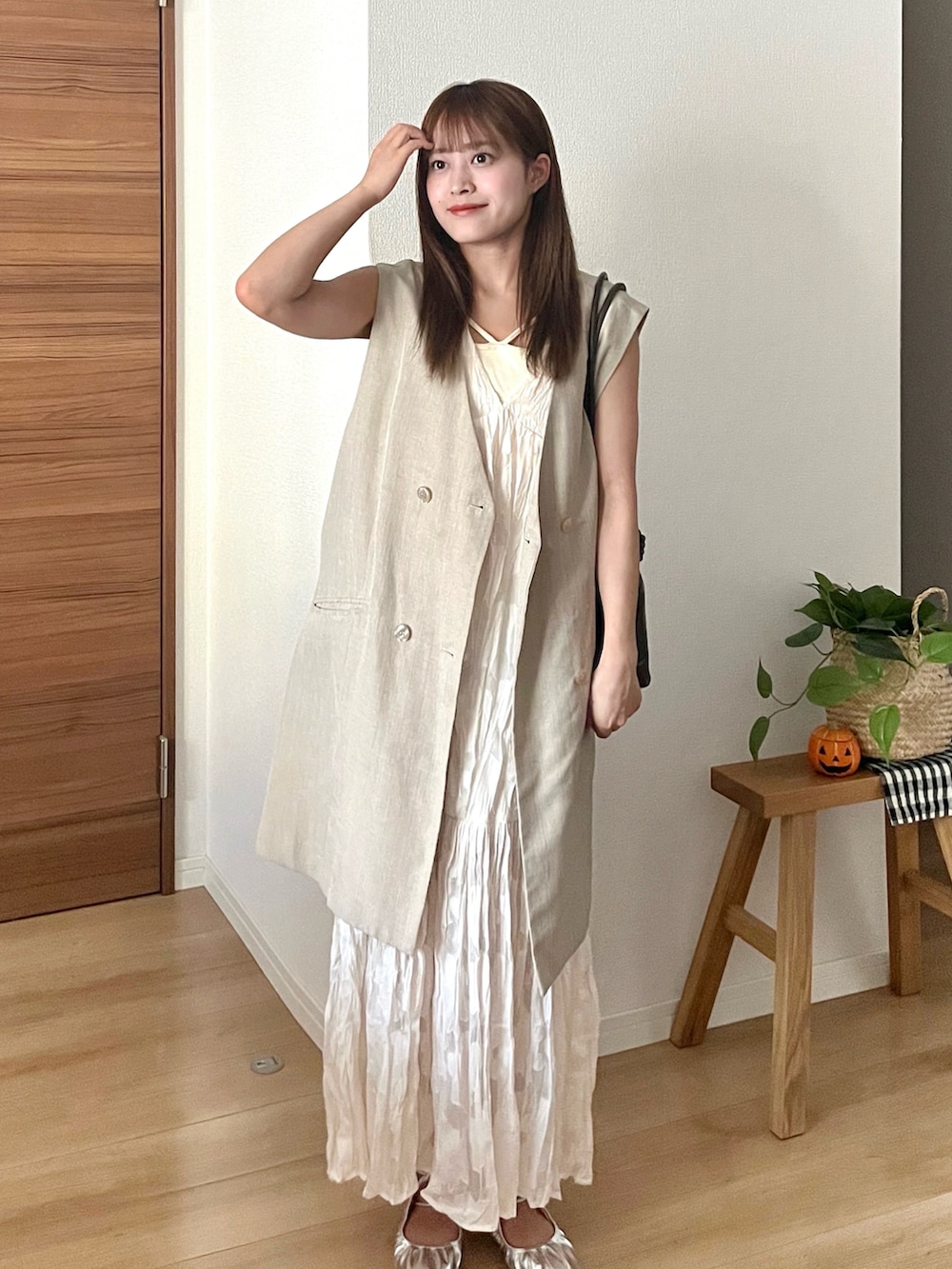 ホワイト系のワンピース、ベージュ系のベスト、ブラウン系のショルダーバッグを着用したレディースの秋コーディネートの2枚目の写真