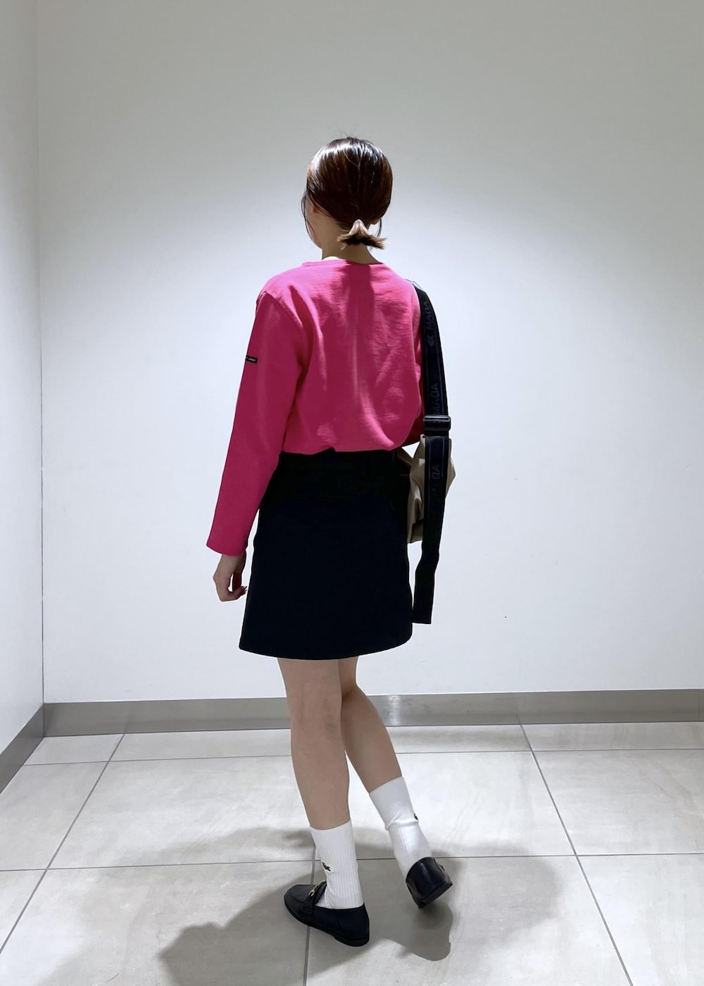 ブラック系のローファー、ブラック系のスカート、ベージュ系のショルダーバッグを着用したレディースの秋コーディネートの3枚目の写真