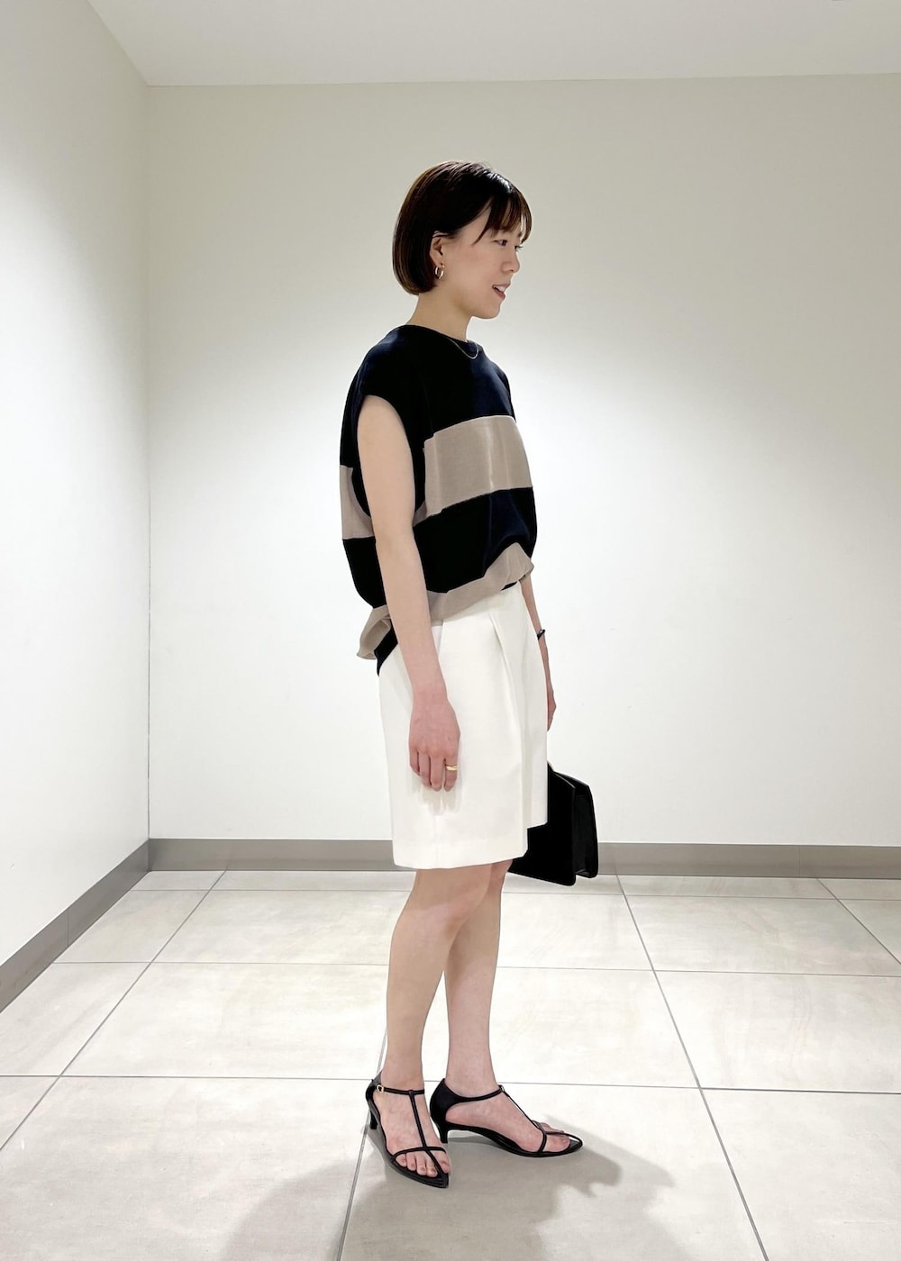 ブラック系のハンドバッグ、ブラック系のサンダル、ホワイト系のその他パンツを着用したレディースの夏コーディネートの2枚目の写真