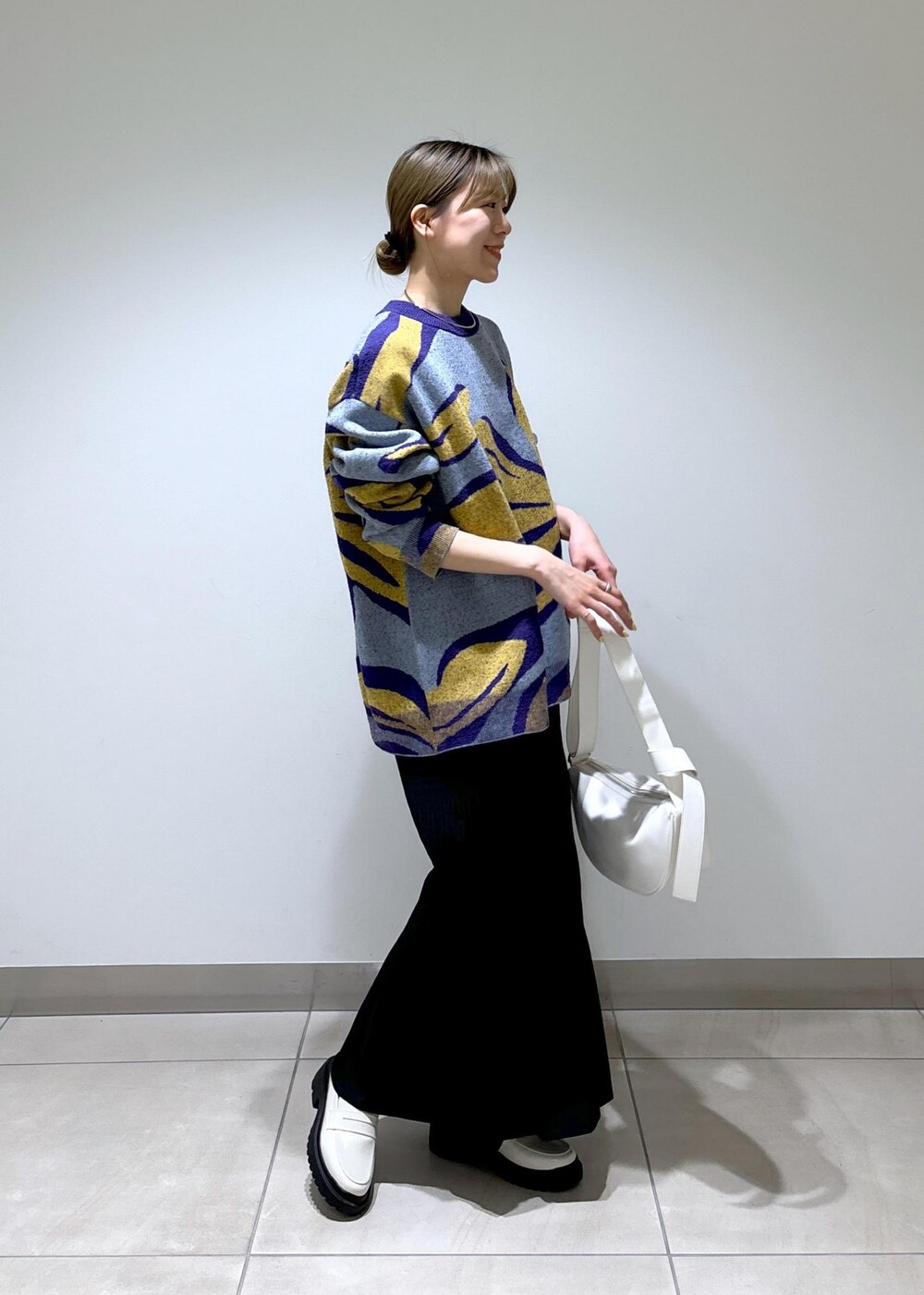 ホワイト系のローファー、ブルー系のニット/セーター、ホワイト系のショルダーバッグを着用したレディースの春コーディネートの2枚目の写真