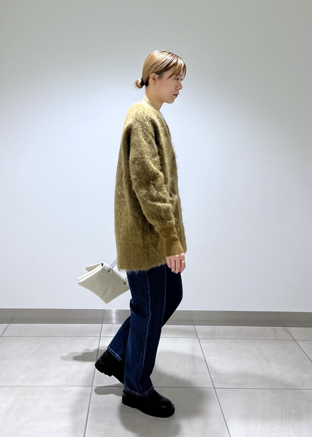 ブラウン系のカーディガン/ボレロ、ブラック系のブーツ、ブルー系のデニムパンツを着用したレディースの秋コーディネートの2枚目の写真