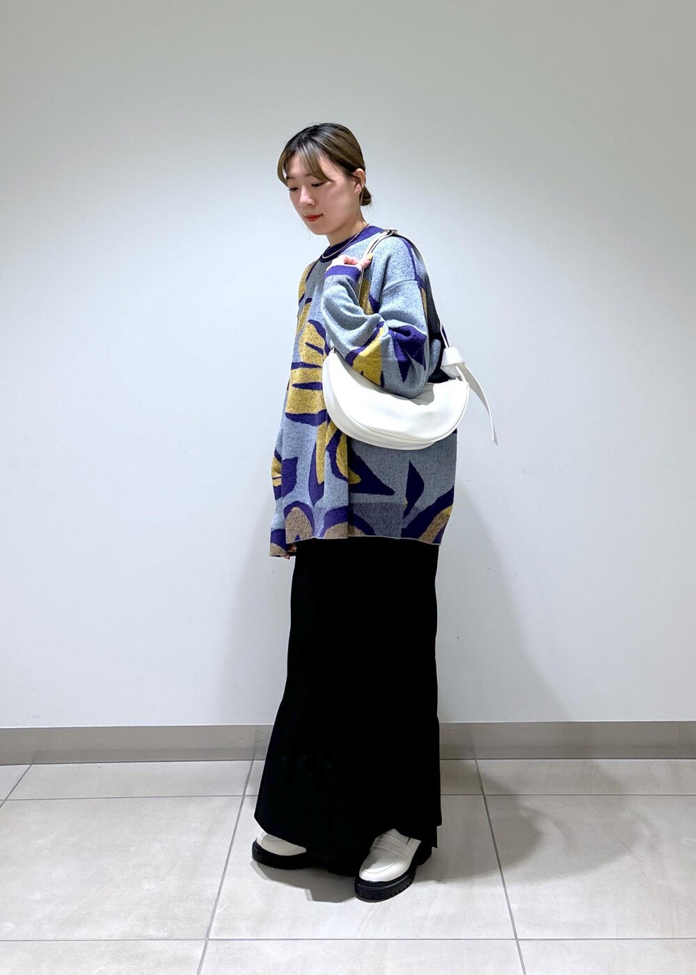 ホワイト系のローファー、ブルー系のニット/セーター、ホワイト系のショルダーバッグを着用したレディースの春コーディネートの3枚目の写真