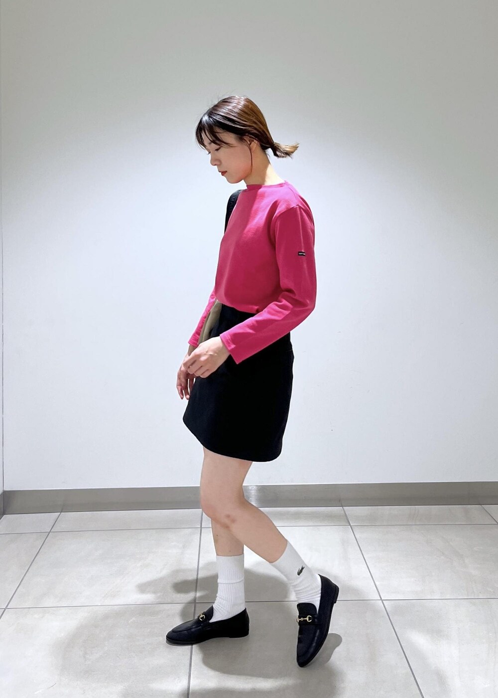 ブラック系のローファー、ブラック系のスカート、ベージュ系のショルダーバッグを着用したレディースの秋コーディネートの2枚目の写真