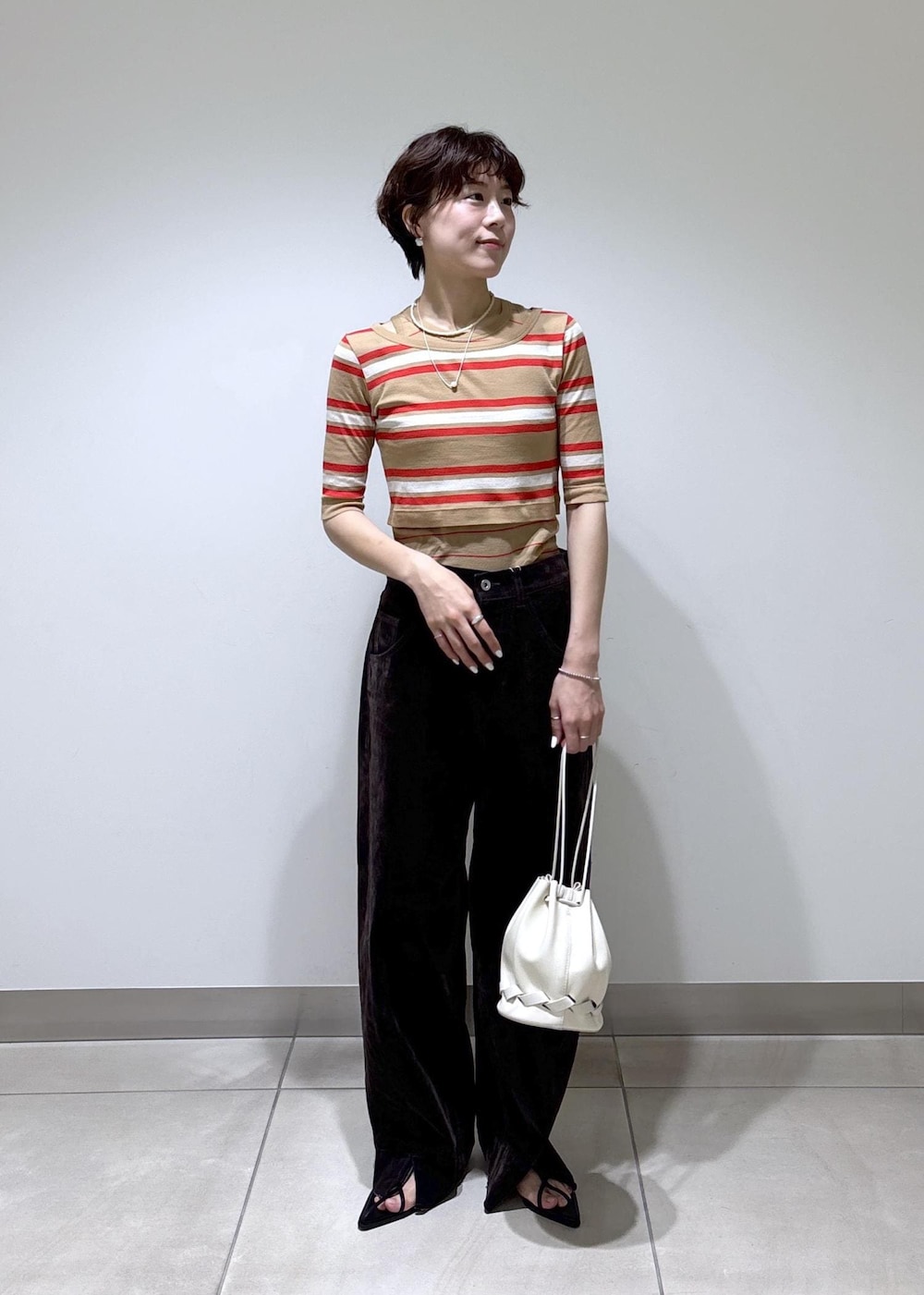ブラック系のサンダル、ホワイト系のショルダーバッグ、ブラウン系のデニムパンツを着用したレディースの夏コーディネートの2枚目の写真