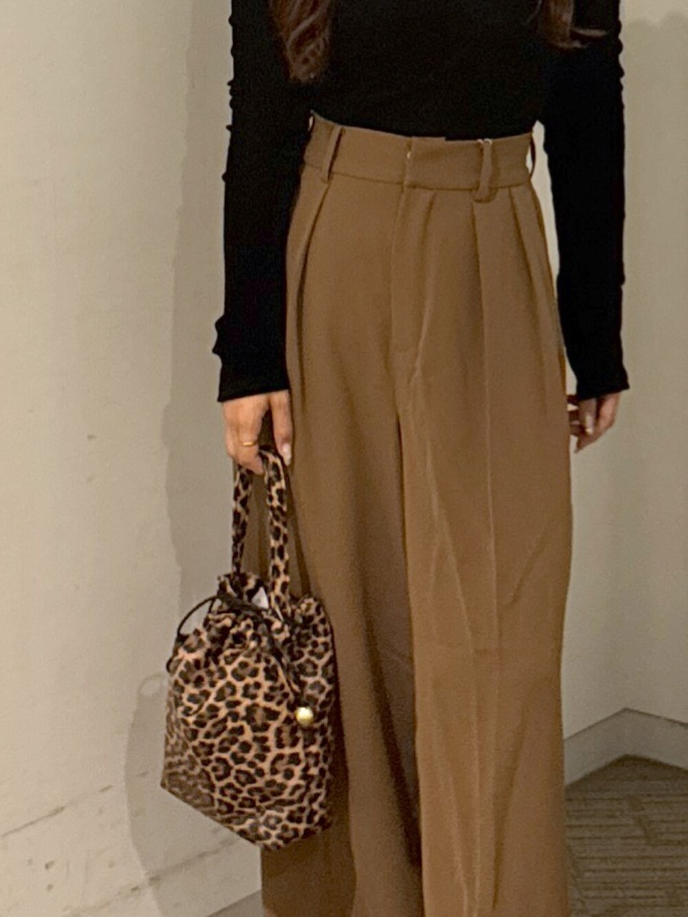 ブラウン系のスラックス、ブラック系のショルダーバッグ、ホワイト系のキャミソールを着用したレディースの秋コーディネートの4枚目の写真