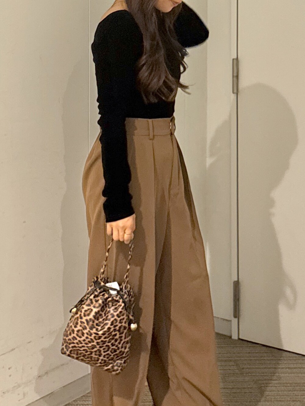 ブラウン系のスラックス、ブラック系のショルダーバッグ、ホワイト系のキャミソールを着用したレディースの秋コーディネートの2枚目の写真