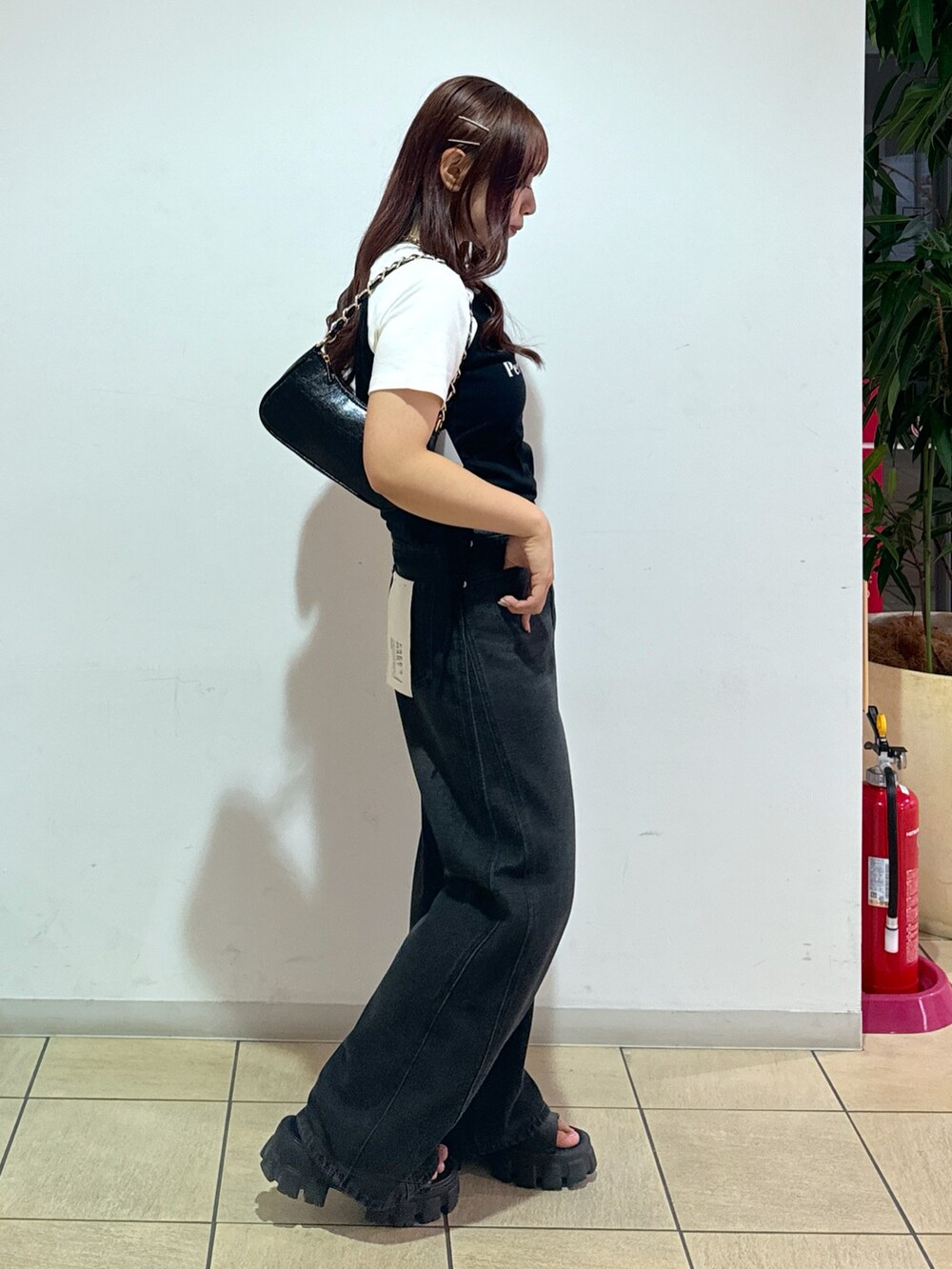 ブルー系のデニムパンツ、ブラック系のトートバッグ、レッド系のTシャツ/カットソーを着用したレディースの夏コーディネートの2枚目の写真