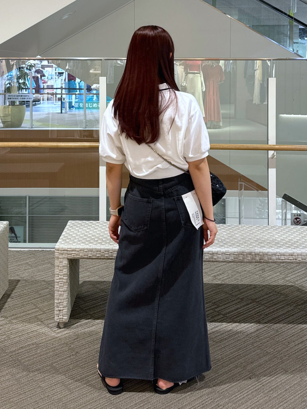 ホワイト系のポロシャツ、ブラック系のショルダーバッグ、ブラック系のデニムスカートを着用したレディースの春コーディネートの3枚目の写真