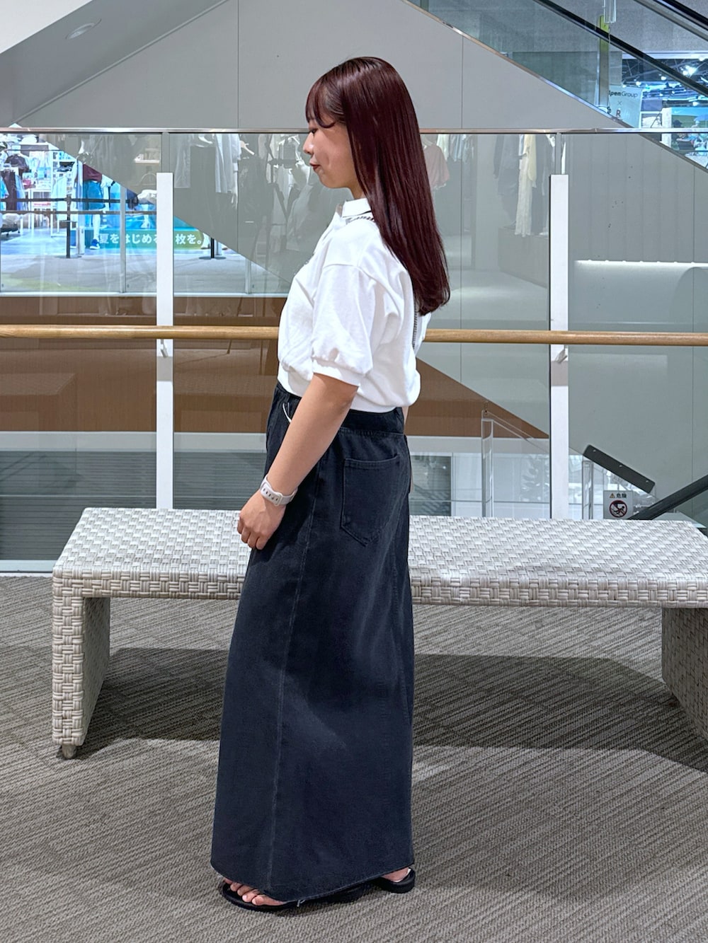 ホワイト系のポロシャツ、ブラック系のショルダーバッグ、ブラック系のデニムスカートを着用したレディースの春コーディネートの2枚目の写真