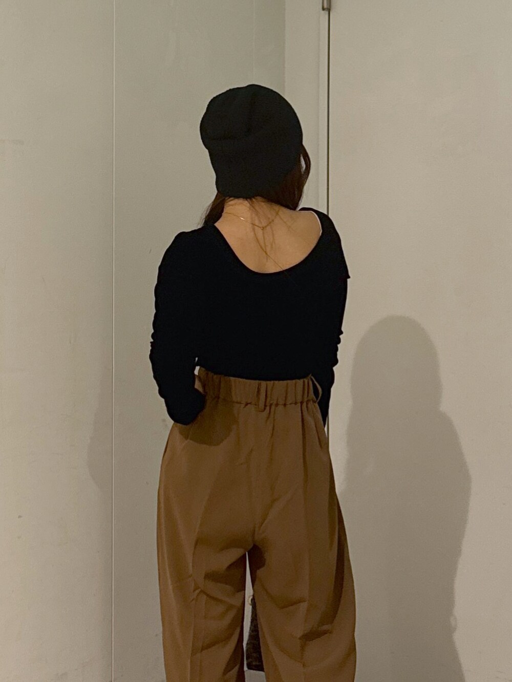 ブラウン系のスラックス、ブラック系のショルダーバッグ、ホワイト系のキャミソールを着用したレディースの秋コーディネートの5枚目の写真