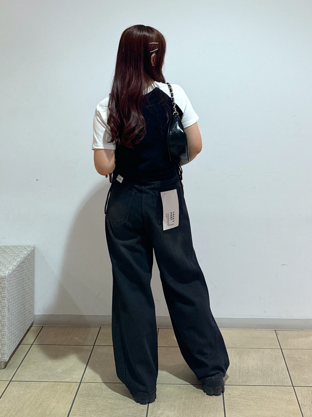 ブルー系のデニムパンツ、ブラック系のトートバッグ、レッド系のTシャツ/カットソーを着用したレディースの夏コーディネートの3枚目の写真