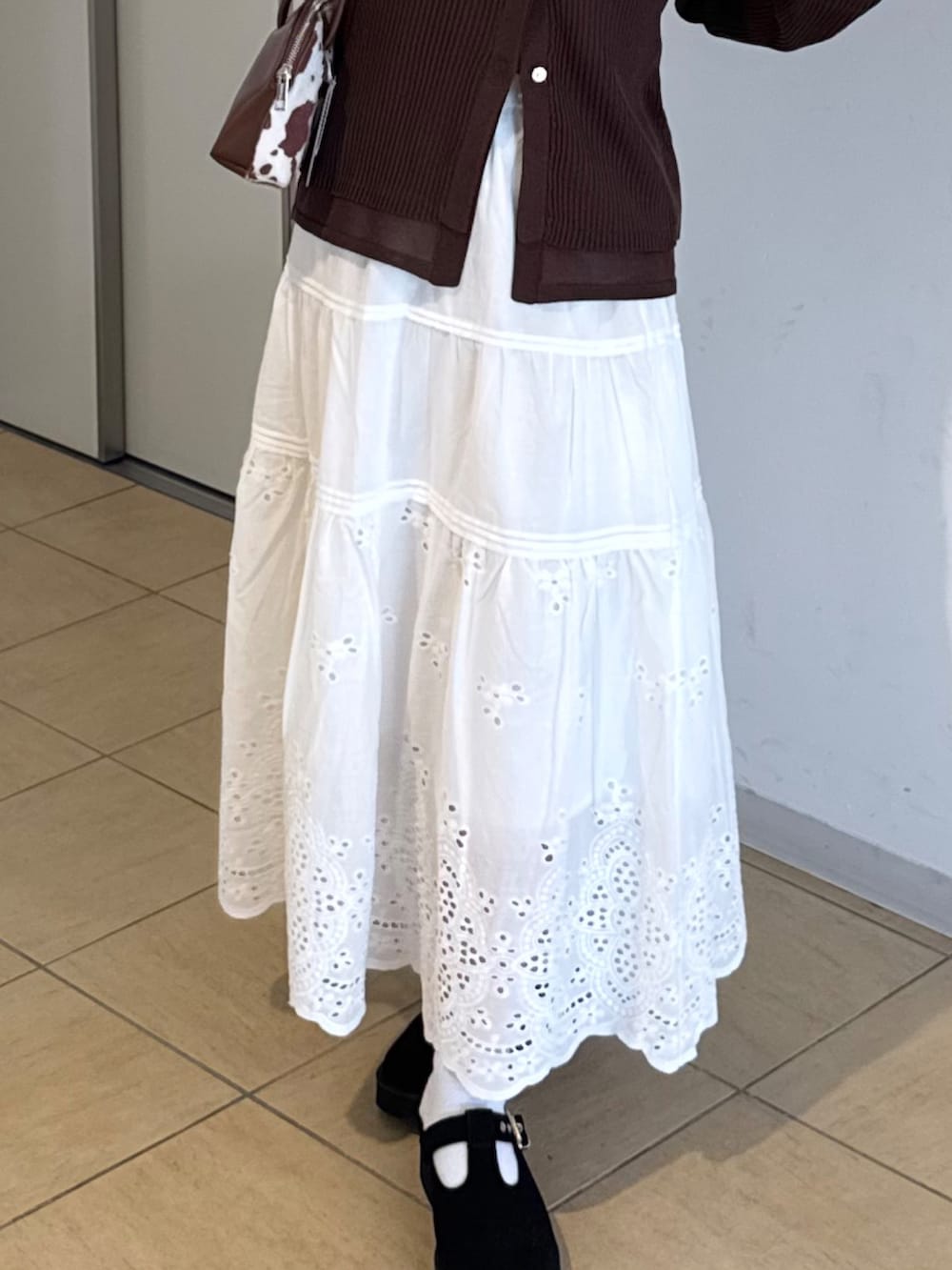 ブラウン系のサンダル、ホワイト系のスカート、ブラウン系のニット/セーターを着用したレディースの秋コーディネートの5枚目の写真