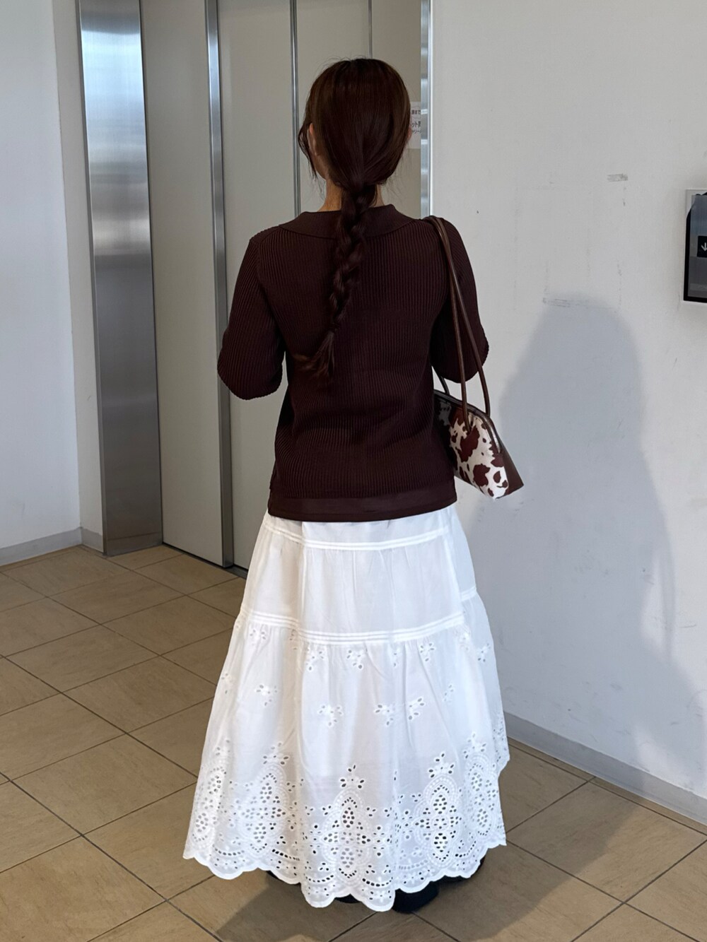 ブラウン系のサンダル、ホワイト系のスカート、ブラウン系のニット/セーターを着用したレディースの秋コーディネートの2枚目の写真
