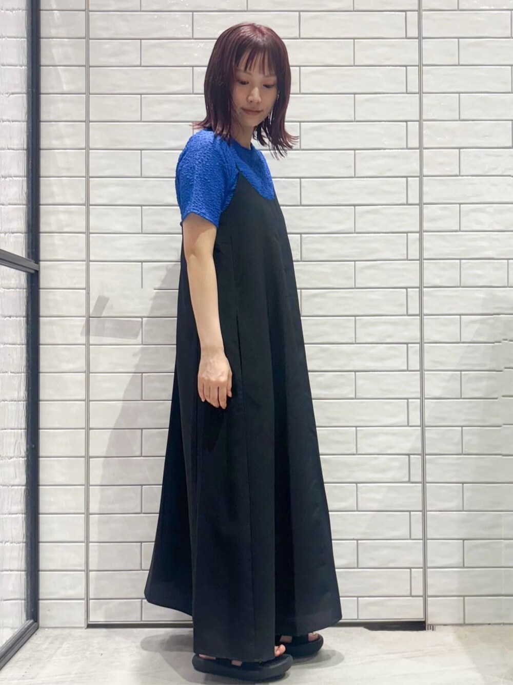 ブルー系のTシャツ/カットソー、ブラック系のワンピース、ベージュ系のショルダーバッグを着用したレディースの夏コーディネートの2枚目の写真