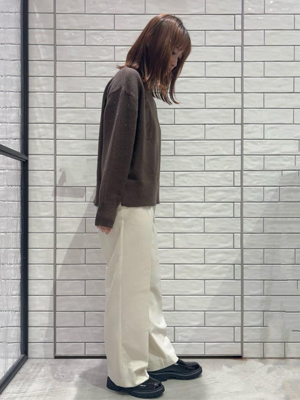 ブラウン系のニット/セーター、ホワイト系のその他パンツ、ブラック系のパンプスを着用したレディースの冬コーディネートの3枚目の写真