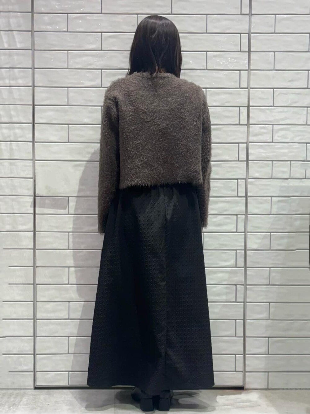 ブラウン系のカーディガン/ボレロ、ブラック系のスカート、ホワイト系のハンドバッグを着用したレディースの冬コーディネートの3枚目の写真