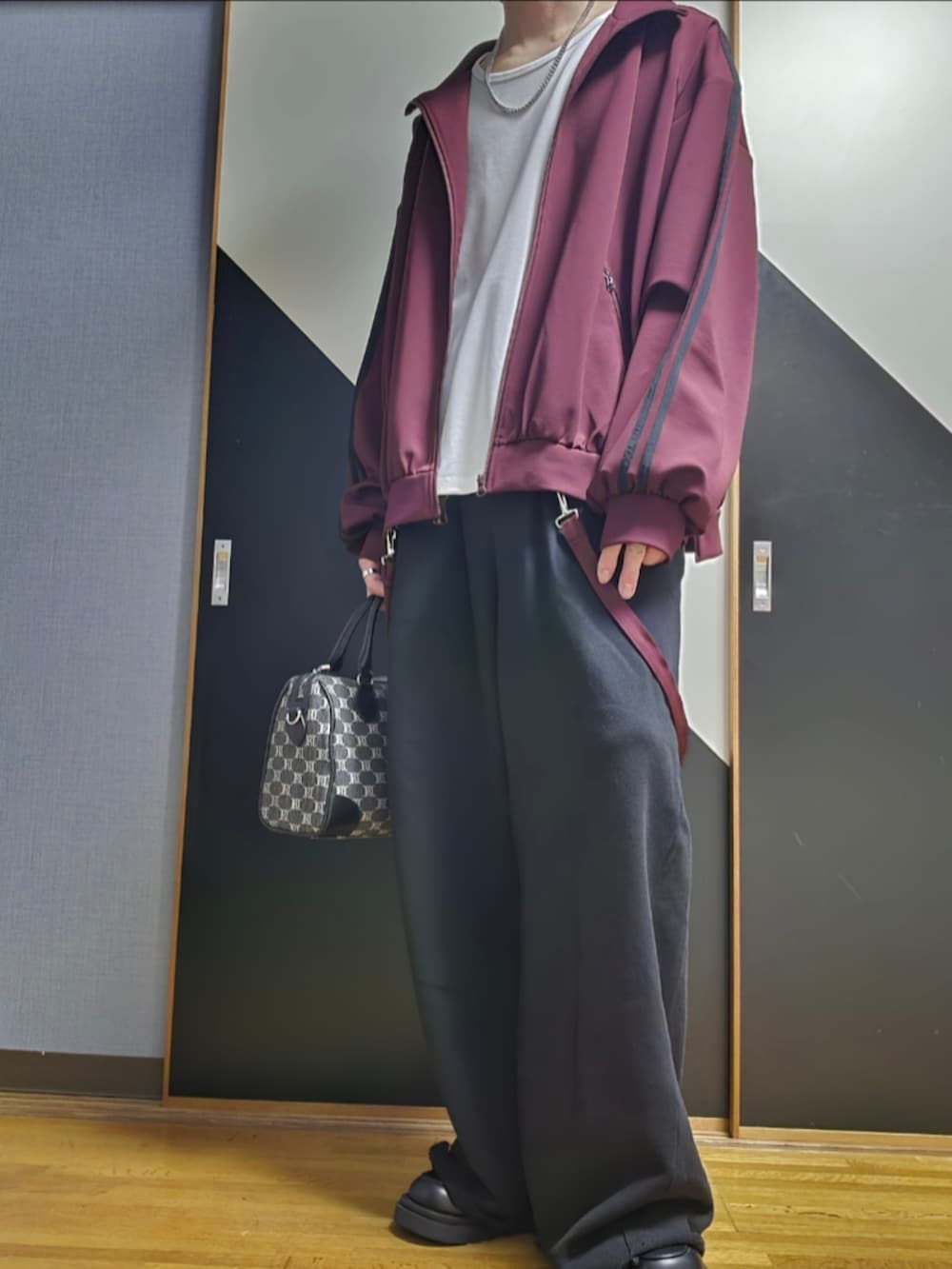 ブラック系のショルダーバッグ、レッド系のブルゾン、ホワイト系のタンクトップを着用したメンズの春コーディネートの2枚目の写真
