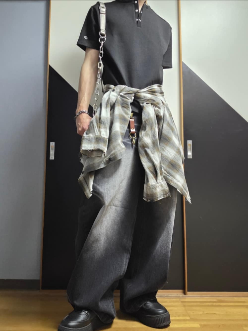 ブラック系のローファー、ブラック系のデニムパンツ、シルバー系のショルダーバッグを着用したメンズの夏コーディネートの2枚目の写真