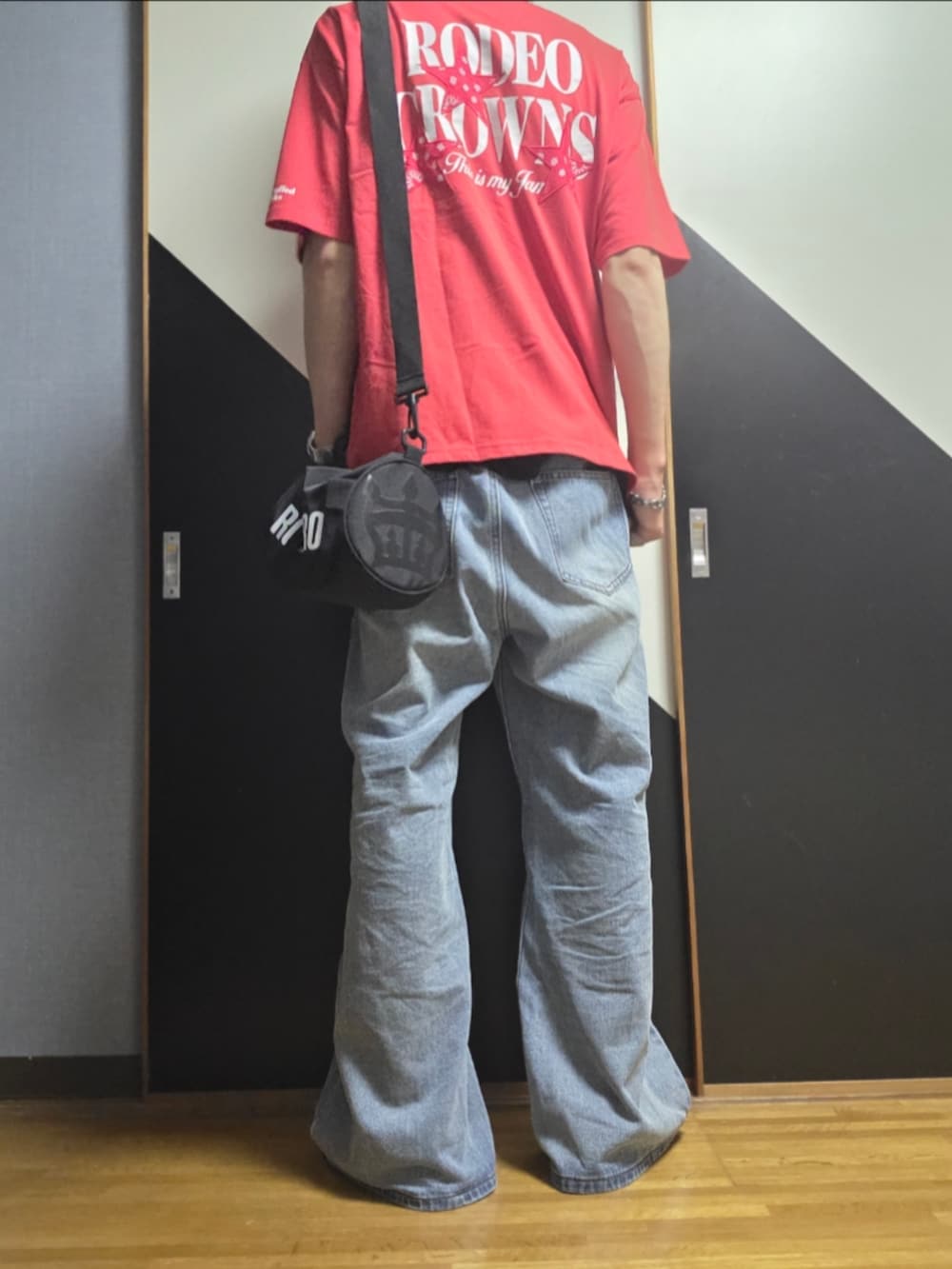 ブルー系のデニムパンツ、ブラック系のショルダーバッグ、ブラック系のタンクトップを着用したメンズの夏コーディネートの2枚目の写真