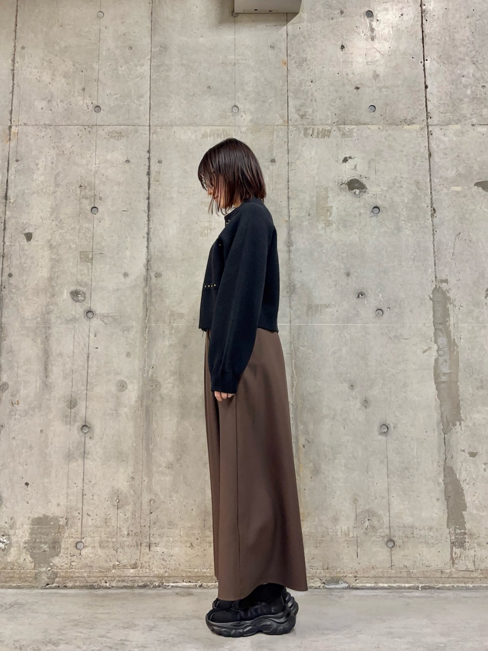 ブラウン系のスカート、ブラック系のカーディガン/ボレロ、ブラック系のスニーカーを着用したレディースの冬コーディネートの3枚目の写真