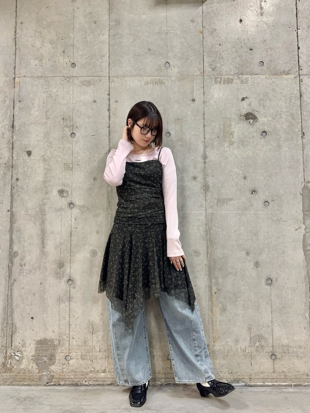ブラック系のワンピース、ピンク系のTシャツ/カットソー、ブルー系のデニムパンツを着用したレディースの春コーディネートの2枚目の写真