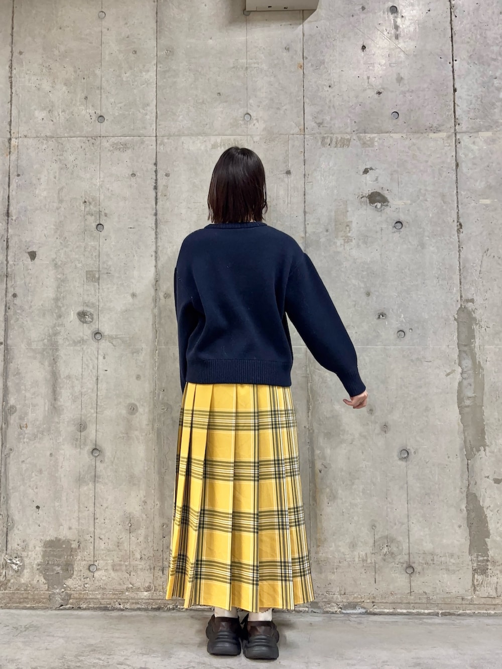 ブルー系のニット/セーター、イエロー系のスカート、ブラウン系のスニーカーを着用したレディースの冬コーディネートの4枚目の写真