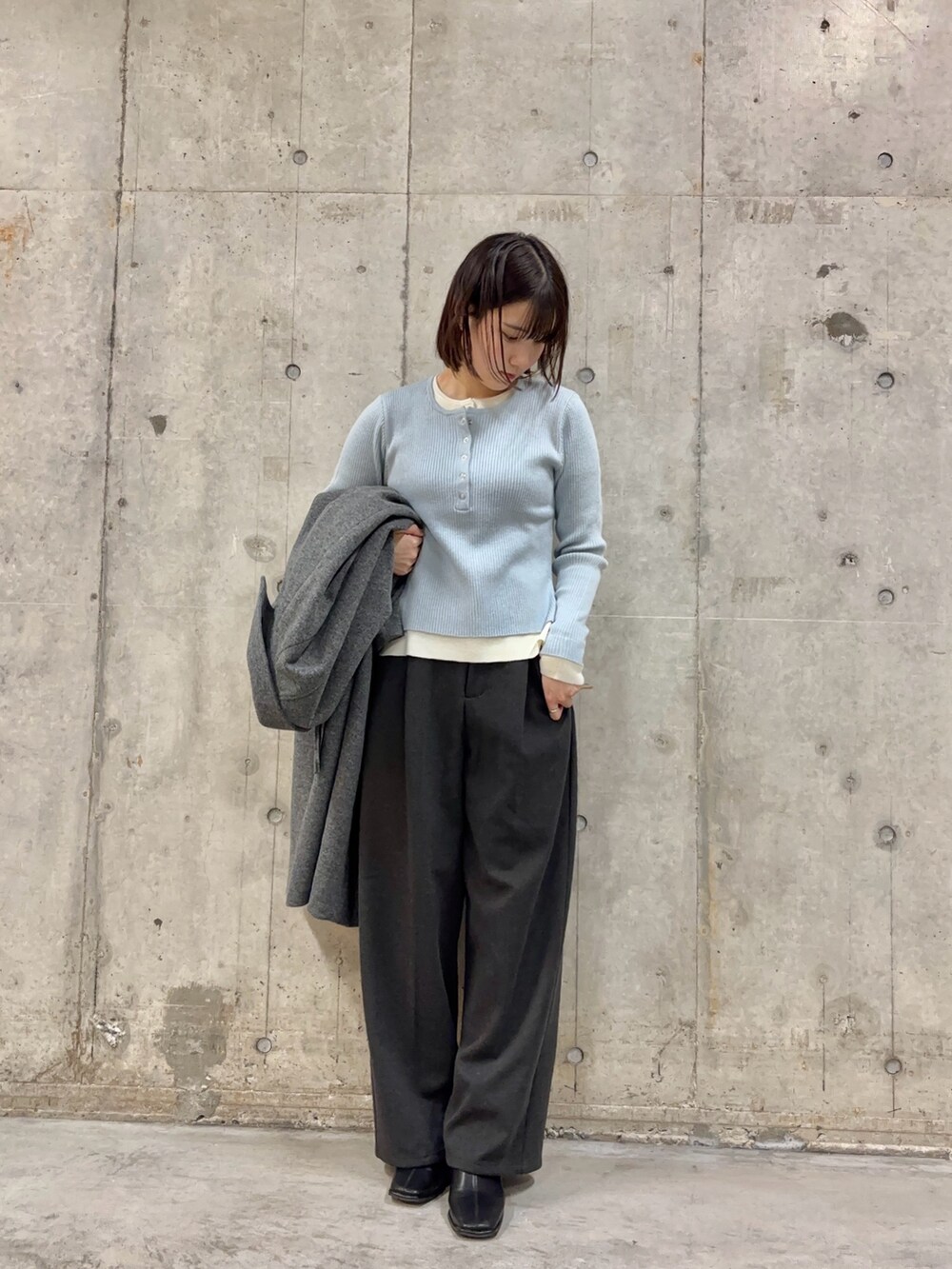 グレー系のその他パンツ、グレー系のステンカラーコート、ブルー系のニット/セーターを着用したレディースの冬コーディネートの2枚目の写真