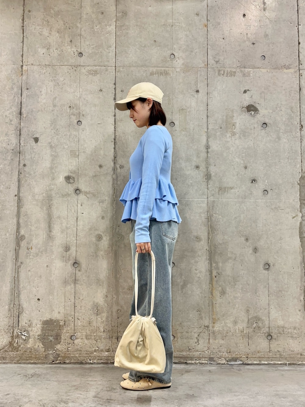 ブルー系のカーディガン/ボレロ、ベージュ系のハンドバッグ、ブルー系のデニムパンツを着用したレディースの冬コーディネートの3枚目の写真