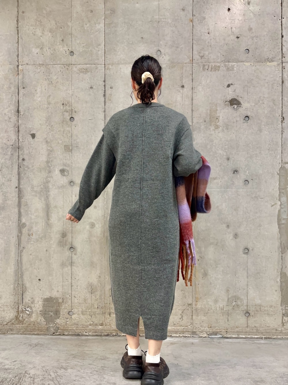 グレー系のワンピース、ブラウン系のスニーカー、オレンジ系のマフラーを着用したレディースの秋コーディネートの4枚目の写真