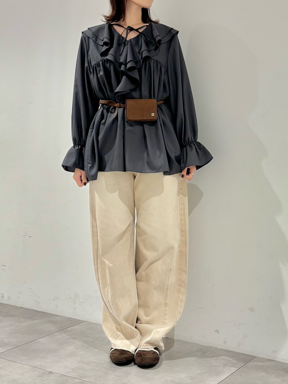 ベージュ系のデニムパンツ、グレー系のワンピース、ブラウン系のスニーカーを着用したレディースの秋コーディネートの3枚目の写真