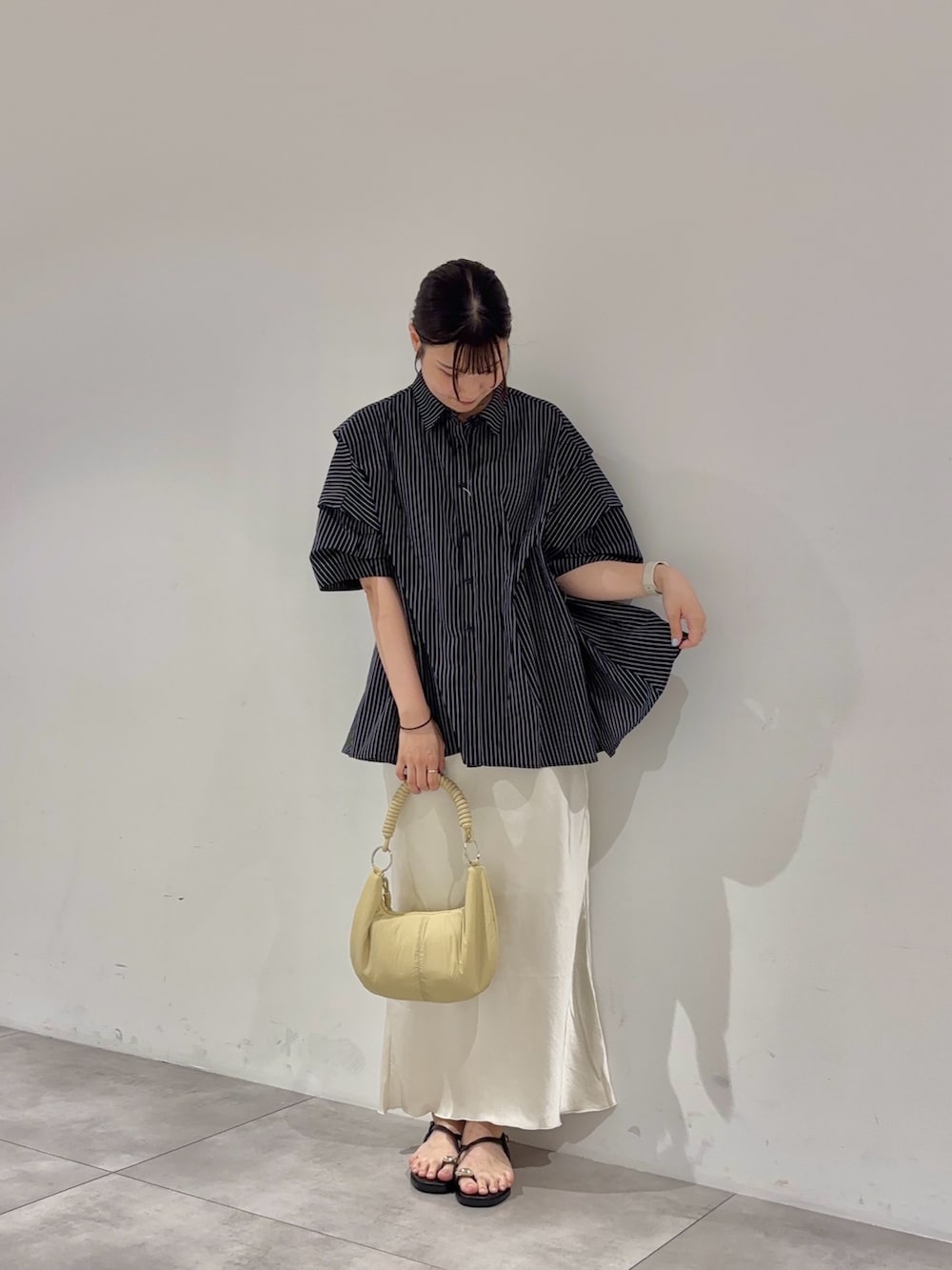 ホワイト系のスカート、ブルー系のシャツ/ブラウス、ベージュ系のハンドバッグを着用したレディースの夏コーディネートの2枚目の写真