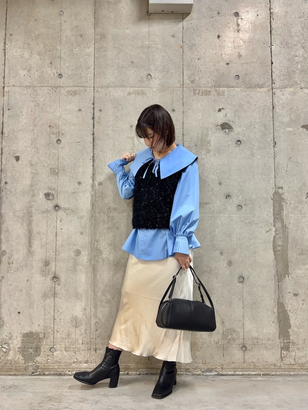 ブラック系のベスト、ブルー系のシャツ/ブラウス、ブラック系のボストンバッグを着用したレディースの冬コーディネートの2枚目の写真