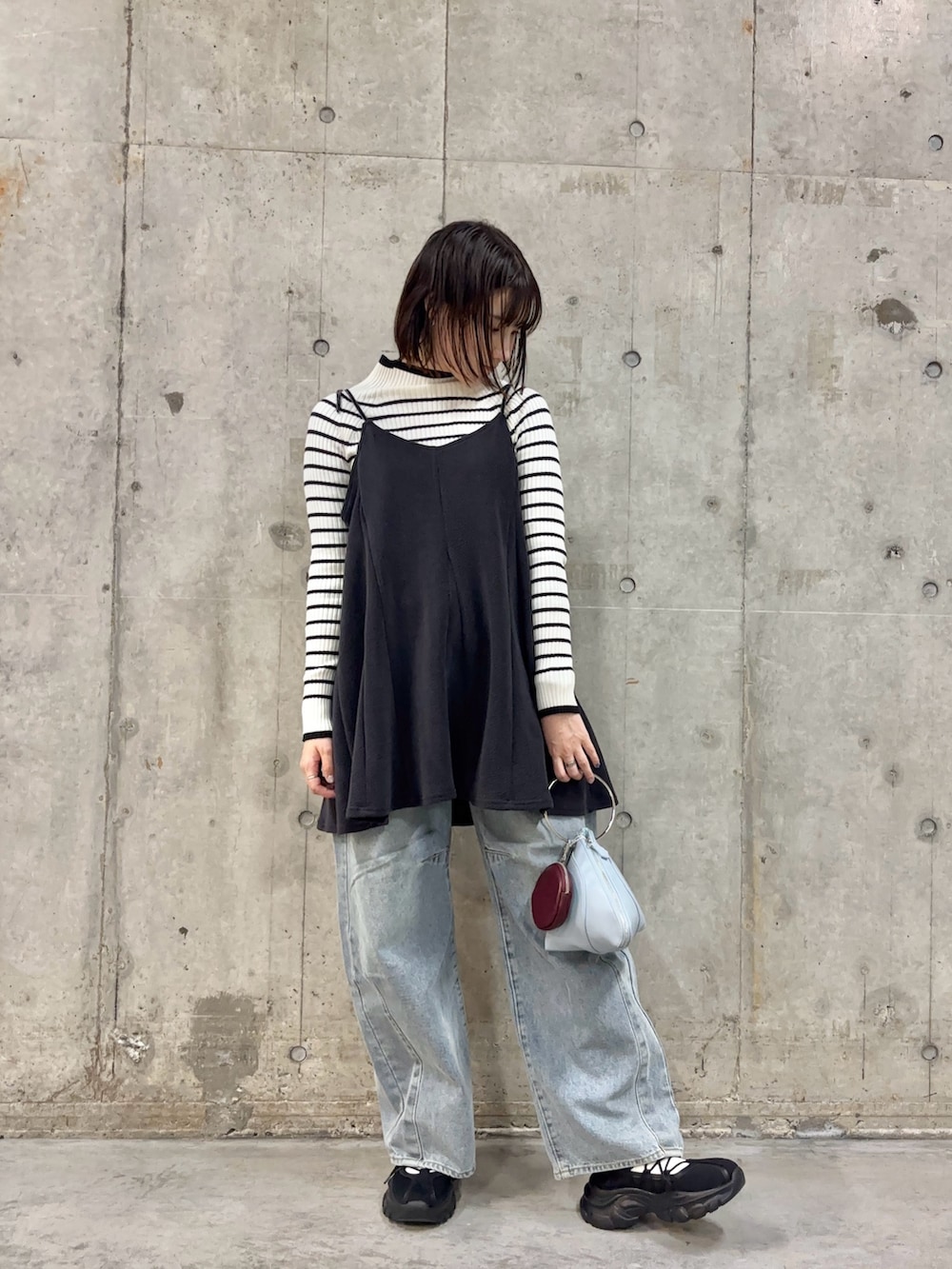 ブルー系のハンドバッグ、ブルー系のデニムパンツ、ブラック系のスニーカーを着用したレディースの冬コーディネートの2枚目の写真