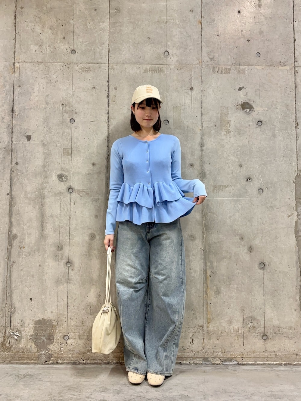 ブルー系のカーディガン/ボレロ、ベージュ系のハンドバッグ、ブルー系のデニムパンツを着用したレディースの冬コーディネートの2枚目の写真