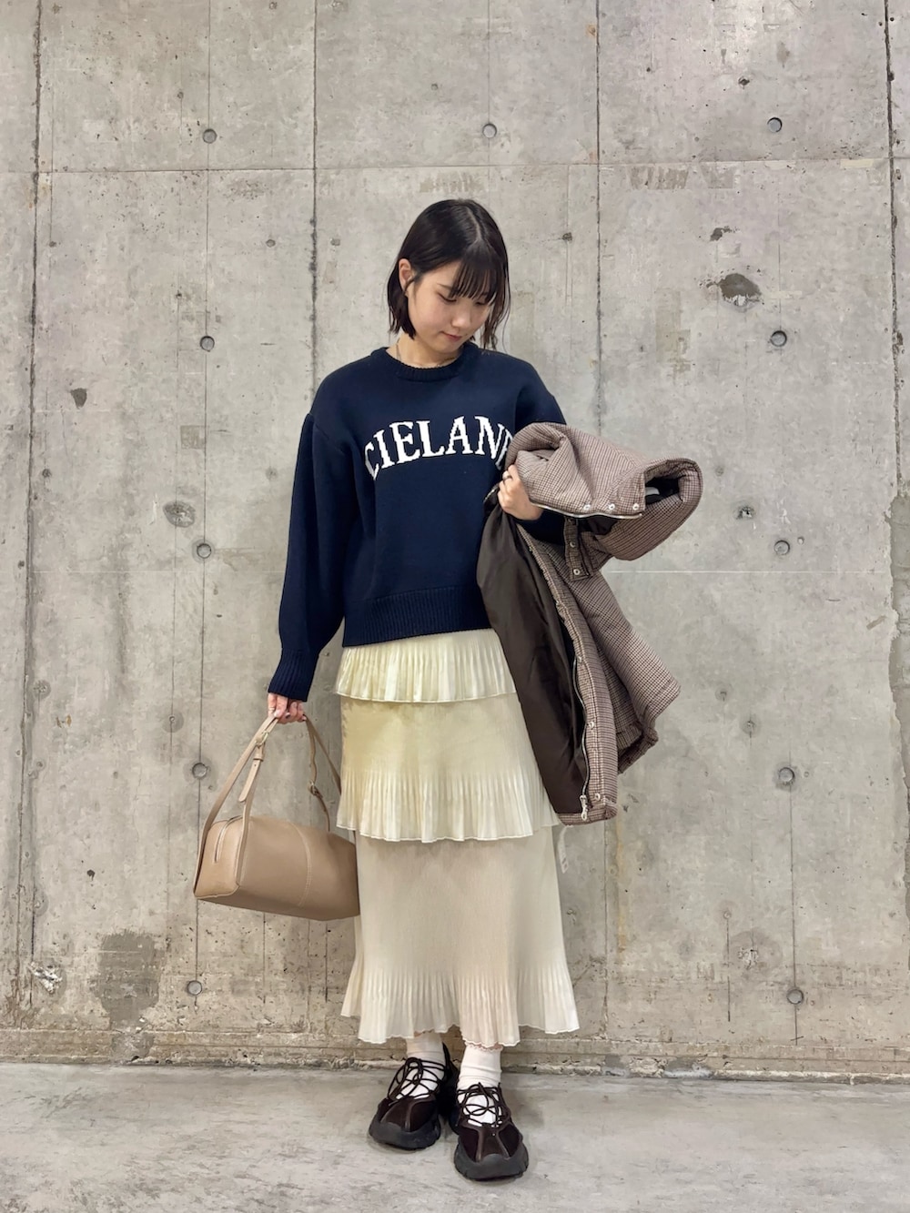 ブラウン系のスニーカー、ホワイト系のスカート、ベージュ系のボストンバッグを着用したレディースの冬コーディネートの3枚目の写真