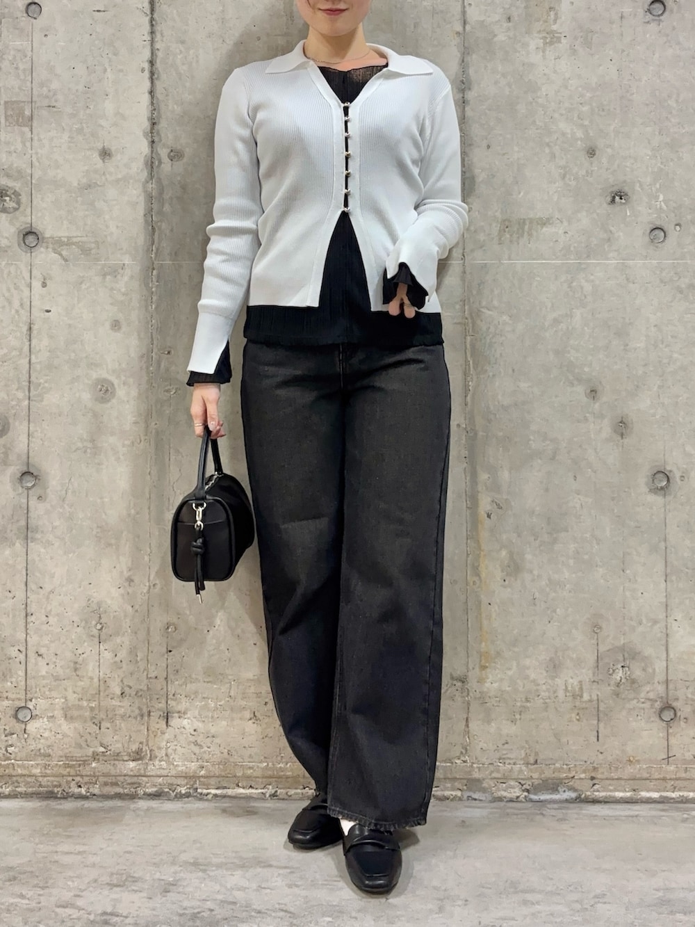 ブラック系のローファー、ブラック系のハンドバッグ、ブラック系のデニムパンツを着用したレディースの冬コーディネートの2枚目の写真