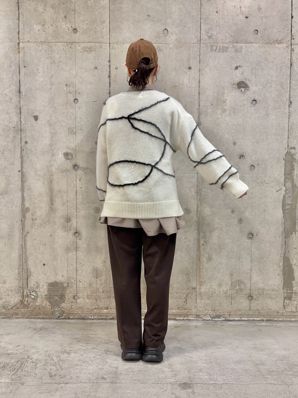 ブラウン系のシャツ/ブラウス、ホワイト系のニット/セーター、ブラウン系のスラックスを着用したレディースの冬コーディネートの4枚目の写真