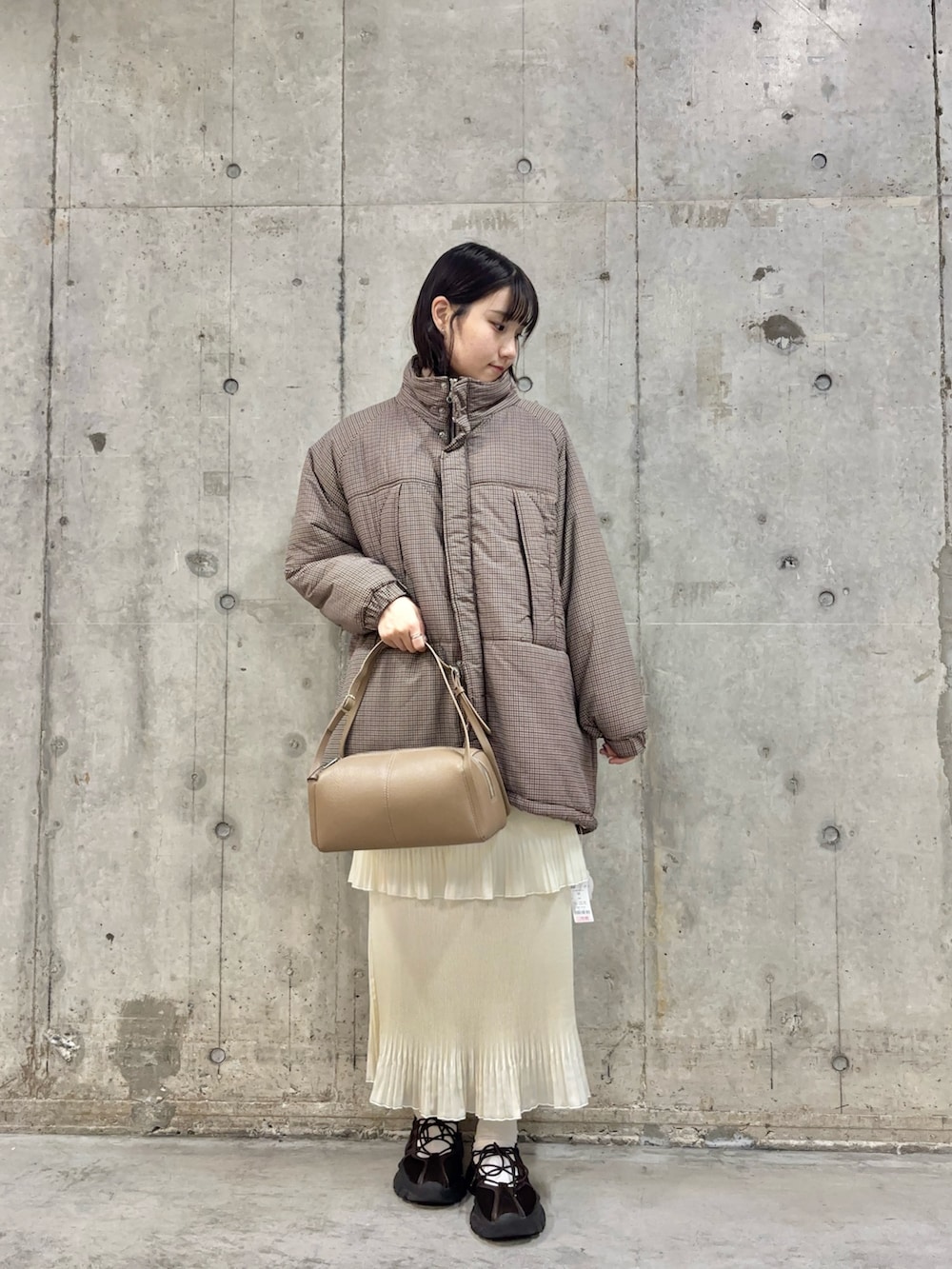 ブラウン系のスニーカー、ホワイト系のスカート、ベージュ系のボストンバッグを着用したレディースの冬コーディネートの2枚目の写真